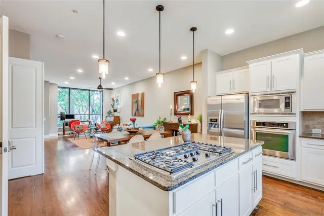 a kitchen with a stove a refrigerator a oven and a dining table with wooden floor