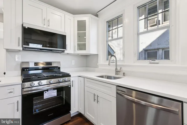 a kitchen with stainless steel appliances a stove microwave and sink