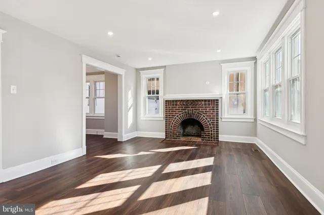a view of a livingroom with a fireplace wooden floor and windows