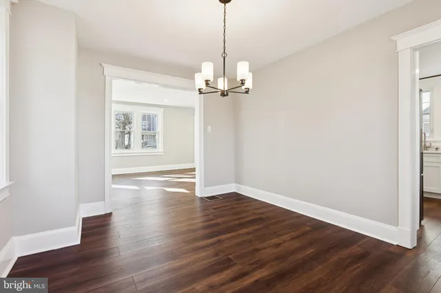 a view of a room with wooden floor chandelier and windows