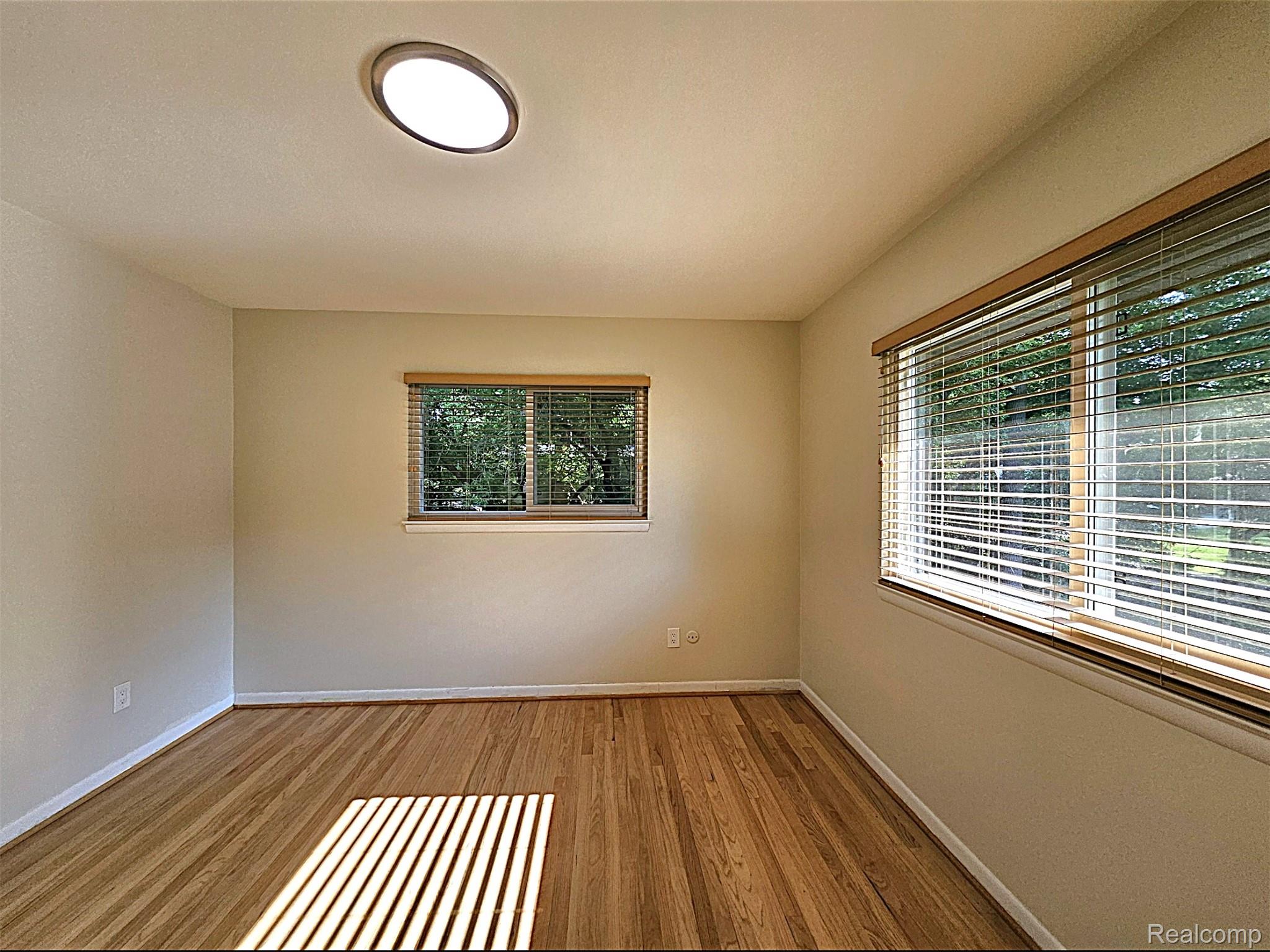 7120 Pebblecreek Road West Bloomfield, MI 48322 - Photo 23 of 31 Light-filled room featuring wood-finish flooring, neutral wall tones, and two windows with blinds