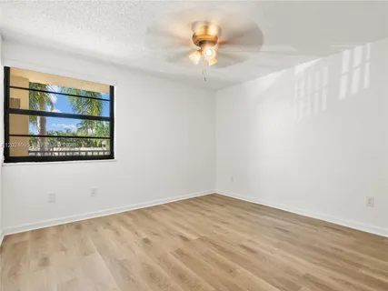 an empty room with a chandelier fan and windows