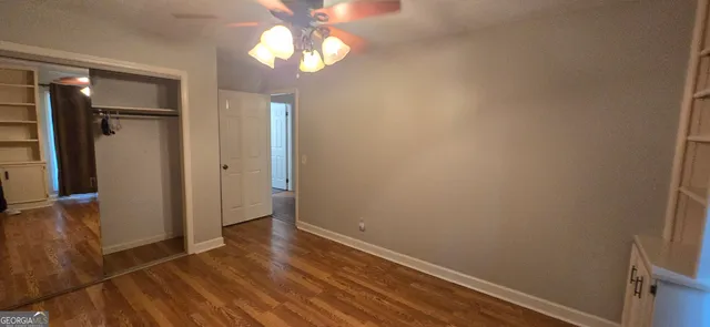 an empty room with wooden floor closet and windows