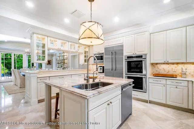 a kitchen with stainless steel appliances granite countertop a sink a stove a refrigerator a center island a stove and a window