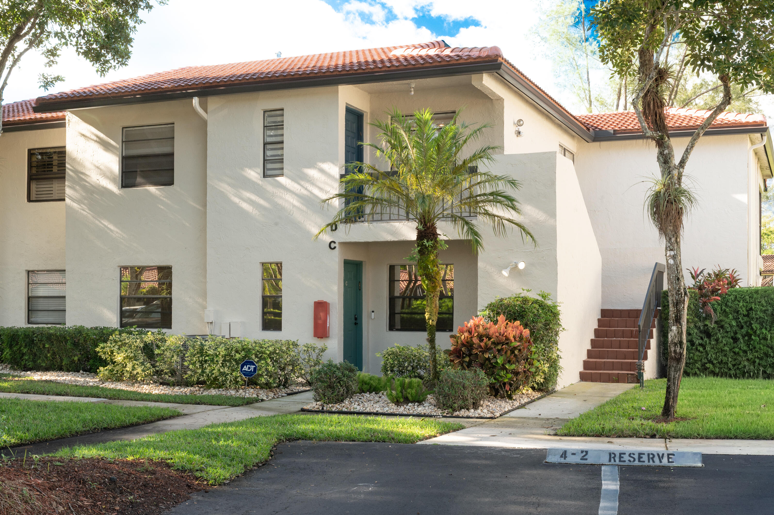 21703 Tall Palm Circle, Unit 5D Boca Raton, FL 33433 - Photo 2 of 36 a front view of a house with a yard and potted plants