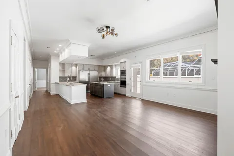 a view of a livingroom with wooden floor and a kitchen