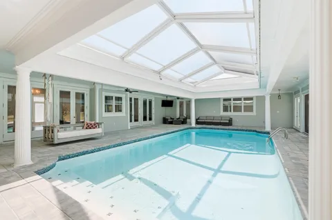 an empty room with a chandelier fan and windows