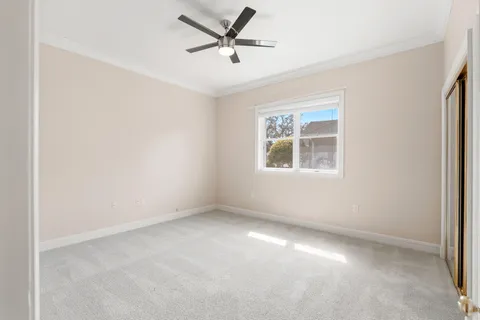 an empty room with ceiling fan and windows
