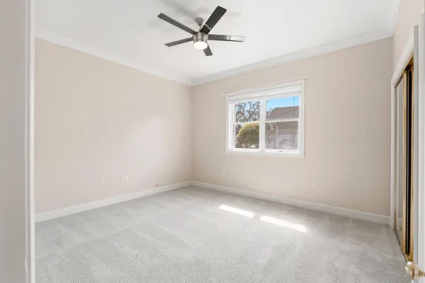 an empty room with ceiling fan and windows