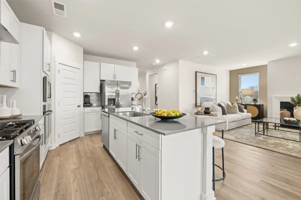 a kitchen that has a lot of white cabinets and stainless steel appliances