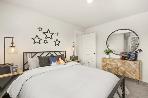 a bedroom with a bed and a potted plant on the dresser