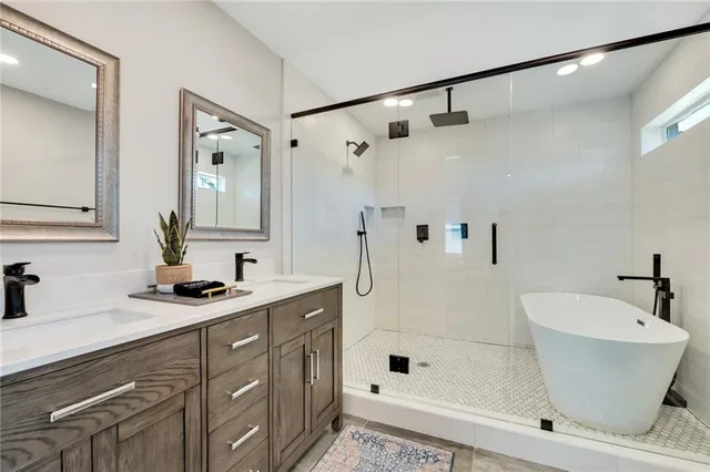 a bathroom with a tub shower sink and mirror
