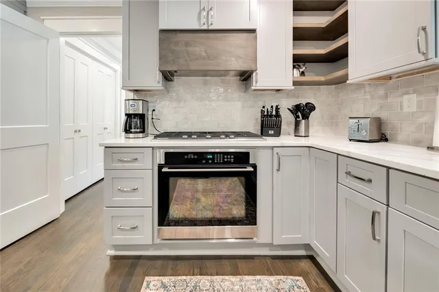 a kitchen with stainless steel appliances granite countertop a stove a sink and white cabinets