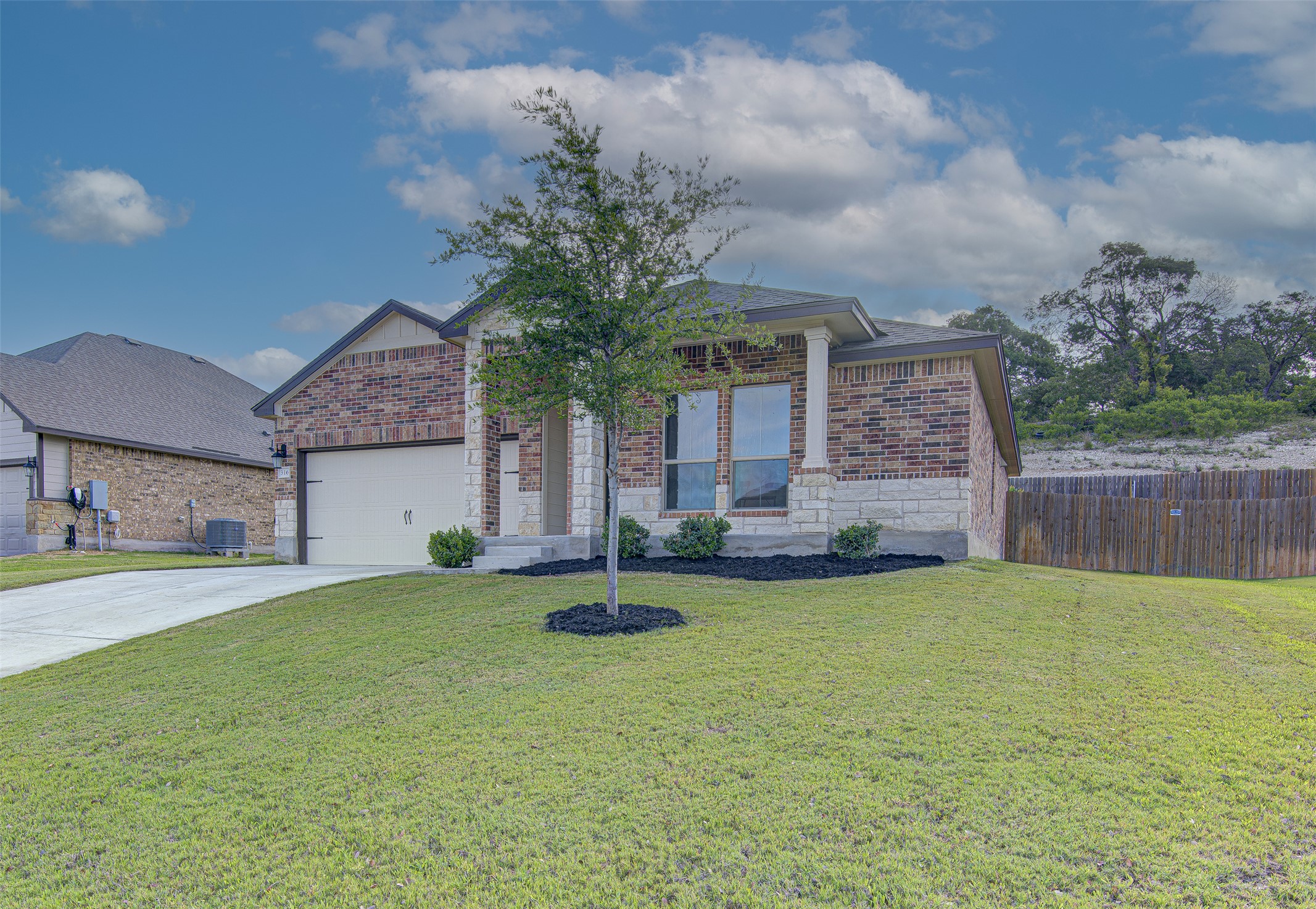 316 Pepper Mill Loop Burnet, TX 78611 - Photo 3 of 27 A charming single-story residence with a brick and stone facade, well-maintained lawn, and a spacious attached garage.