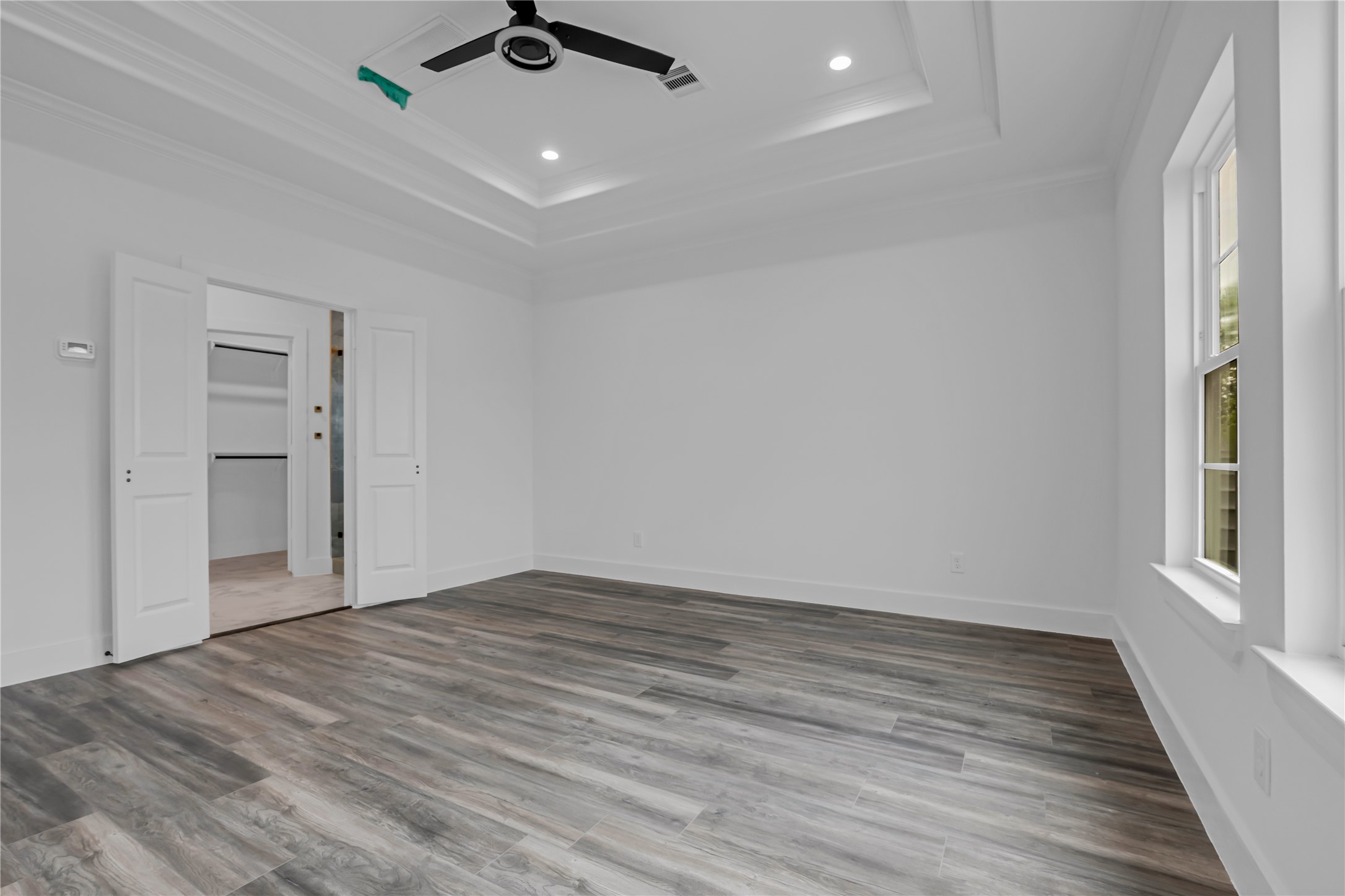 3168 Golfcrest Houston, TX 77087 - Photo 25 of 36 This spacious bedroom boasts elegant tray ceilings, sleek wood flooring, and ample natural light, offering a tranquil retreat with an attached walk-in closet for ultimate convenience.