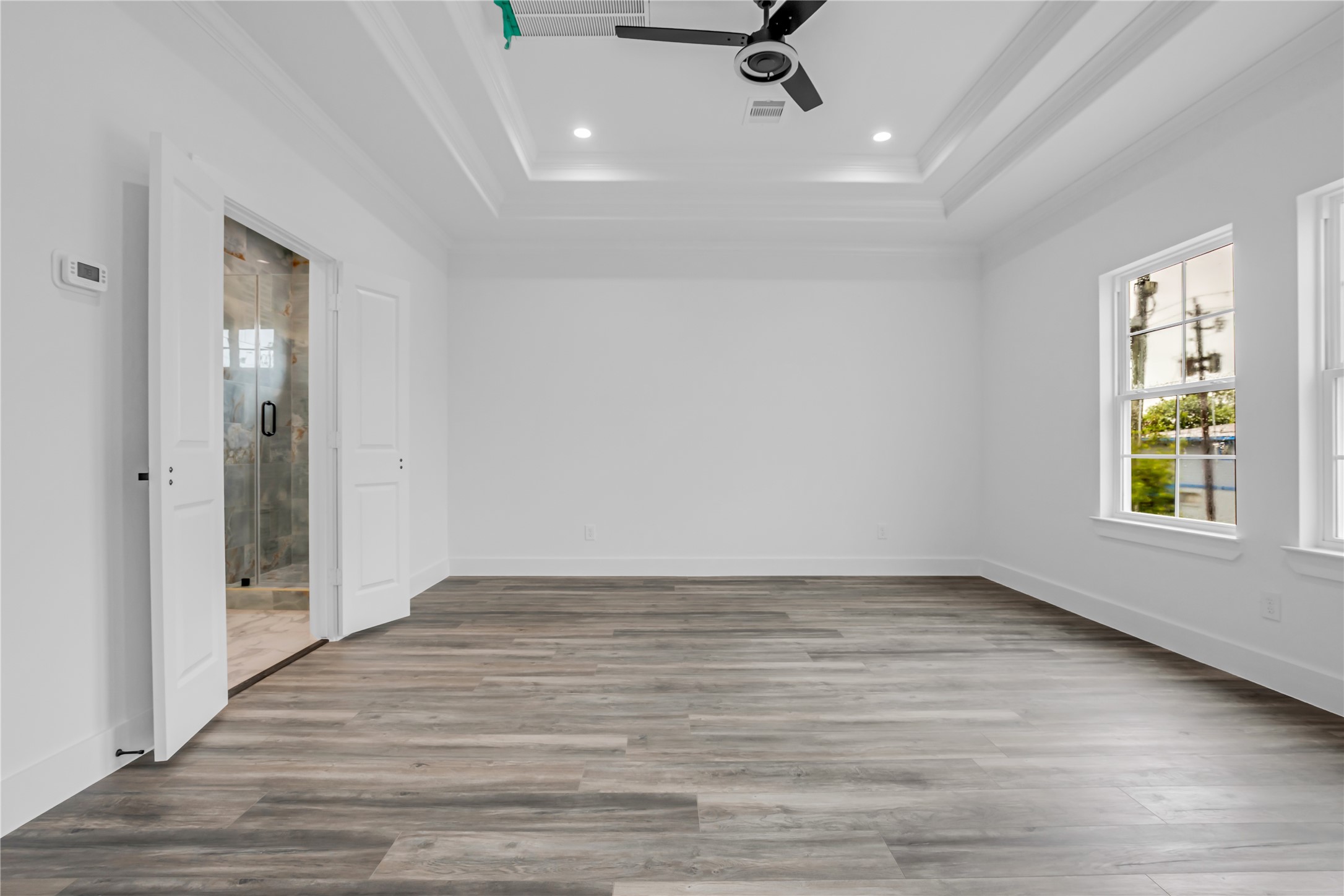 3168 Golfcrest Houston, TX 77087 - Photo 27 of 36 Discover a spacious primary bedroom featuring sleek hardwood floors, abundant natural light from large windows, and an elegant ensuite bathroom with a modern glass shower.