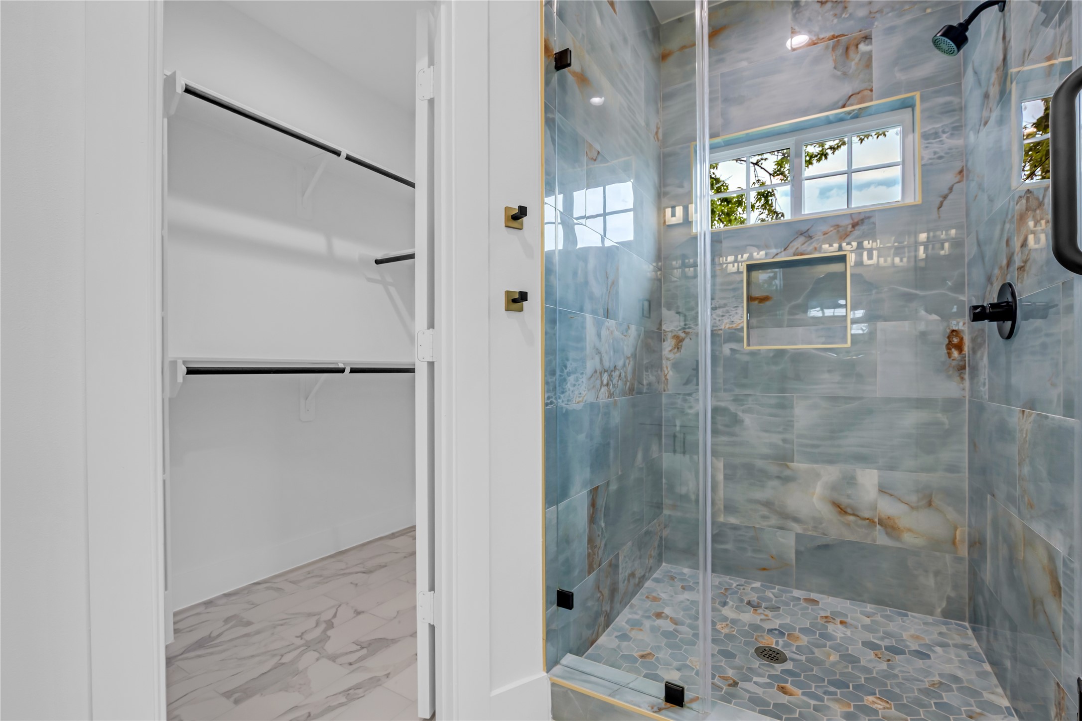 3168 Golfcrest Houston, TX 77087 - Photo 31 of 36 Experience luxury in this primary bathroom, featuring a stunning, modern shower with striking tile work and an adjacent spacious walk-in closet for ultimate convenience.