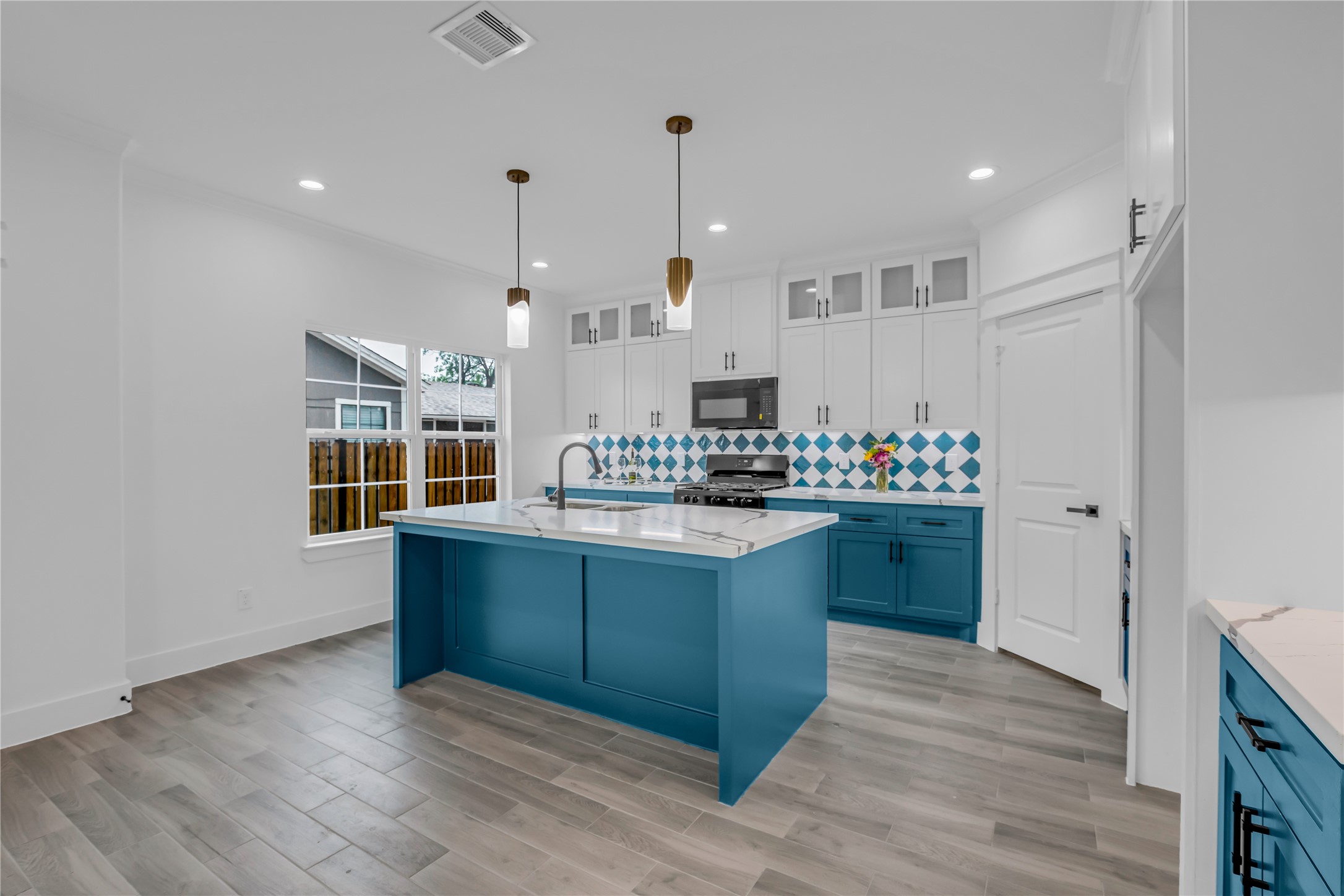3168 Golfcrest Houston, TX 77087 - Photo 9 of 36 This kitchen combines vibrant blue cabinetry with a chic island and eye-catching tile backsplash, creating a bright and inviting space perfect for breakfast gatherings.