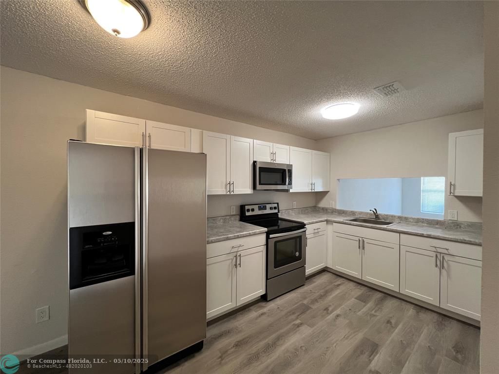 312 Carissa Drive Pahokee, FL 33476 - Photo 2 of 14 a kitchen with stainless steel appliances granite countertop a stove a sink and a refrigerator