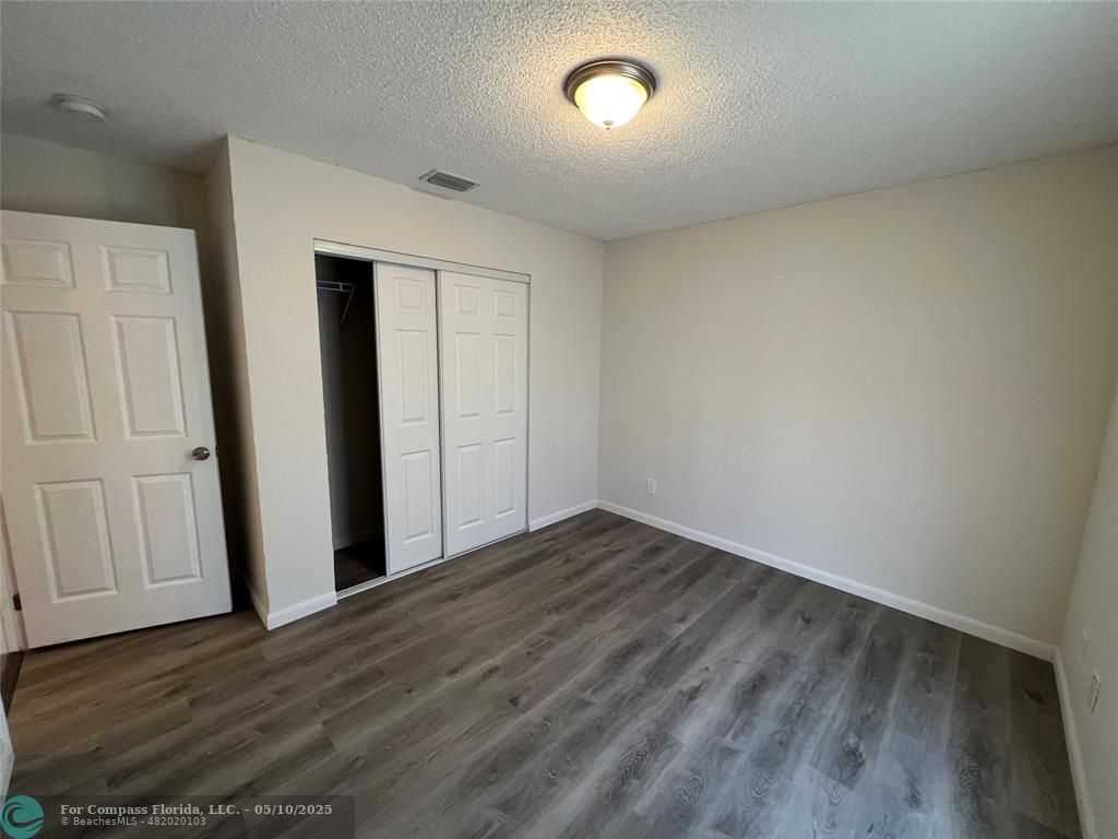 312 Carissa Drive Pahokee, FL 33476 - Photo 6 of 14 an empty room with wooden floor and cabinet