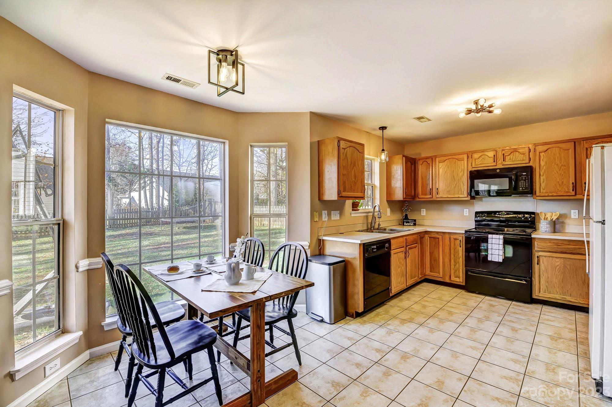 1663 Heather Glen Road Kannapolis, NC 28081 - Photo 8 of 40 a kitchen with stainless steel appliances granite countertop a stove top oven a sink dishwasher a dining table and chairs with wooden floor