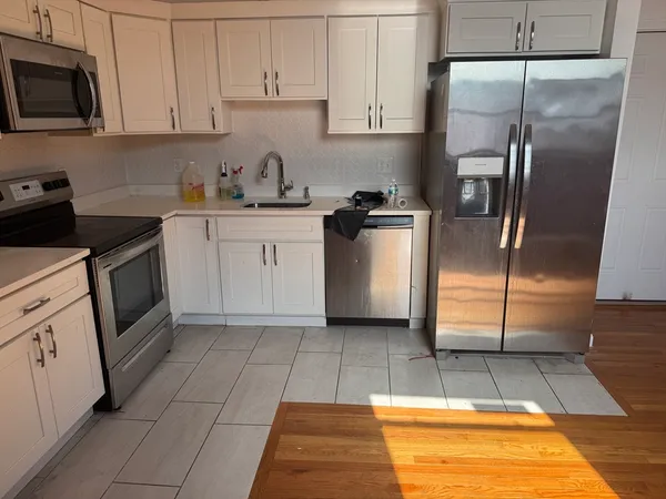 a kitchen with white cabinets a sink and stainless steel appliances