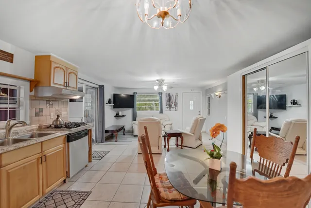 a kitchen with stainless steel appliances granite countertop a sink dishwasher a dining table and chairs with wooden floor