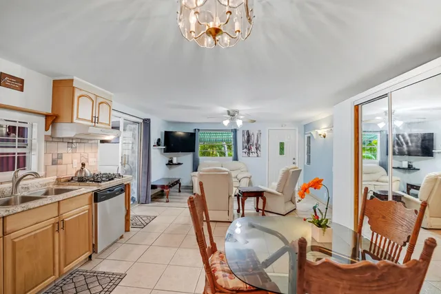 a kitchen with stainless steel appliances granite countertop a sink dishwasher a stove a dining table and chairs with wooden floor