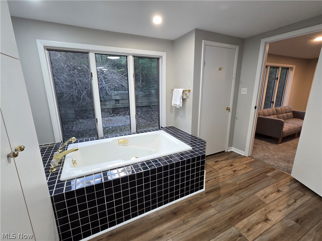 86450 Beaver Dam Road Scio, OH 43988 - Photo 18 of 28 Built-in soaking tub with black tile surround, large window, wood-finish flooring, and recessed lighting