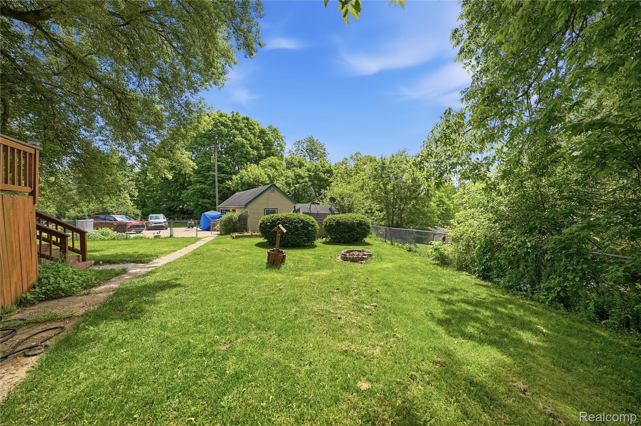 6790 Weyer Road Imlay City, MI 48444 - Photo 29 of 34 Expansive grassy yard featuring established trees, a fire pit, and a pathway leading to a detached structure