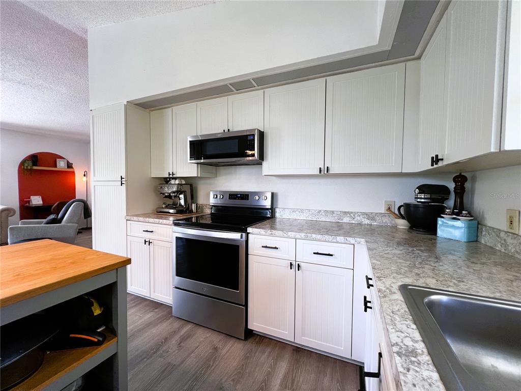 8662 Grand Avenue Boca Grande, FL 33921 - Photo 36 of 68 a kitchen with stainless steel appliances granite countertop a sink dishwasher stove and microwave with wooden floor