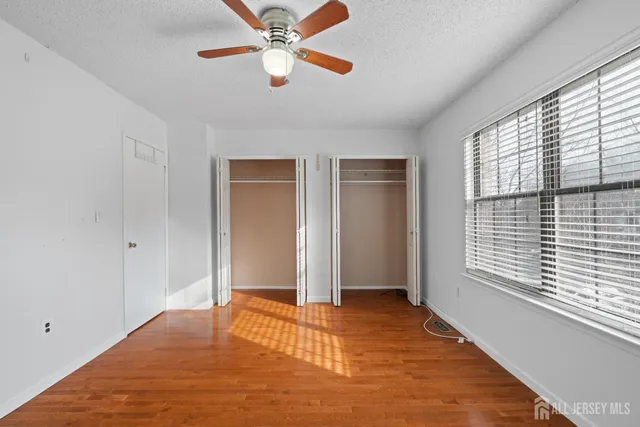 a view of empty room with wooden floor and fan
