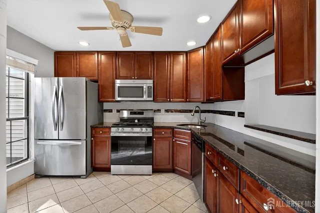 a kitchen with stainless steel appliances granite countertop a refrigerator a stove a sink and dishwasher