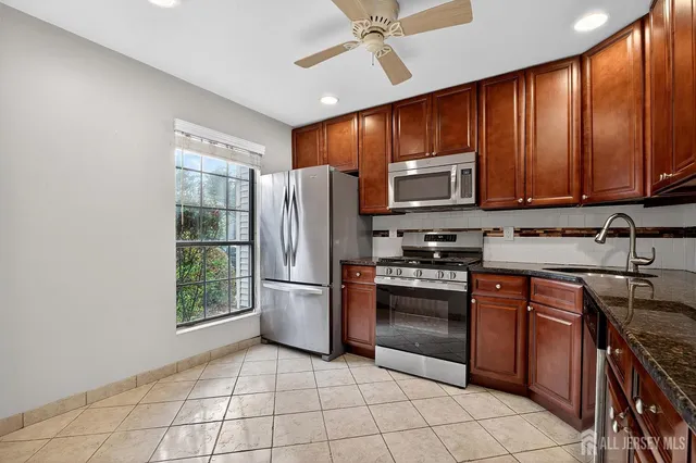 a kitchen with stainless steel appliances granite countertop a stove top oven a sink and a refrigerator