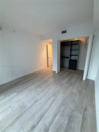 a view of an empty room with a window and a dresser