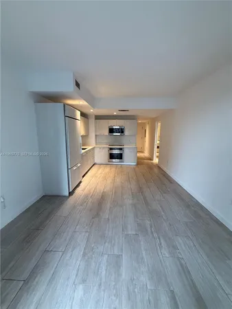an empty room with wooden floor fireplace and windows