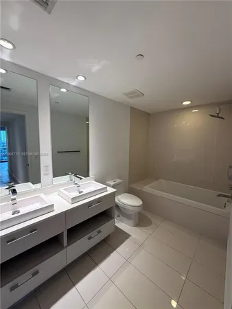 a bathroom with a double vanity sink toilet and bathtub