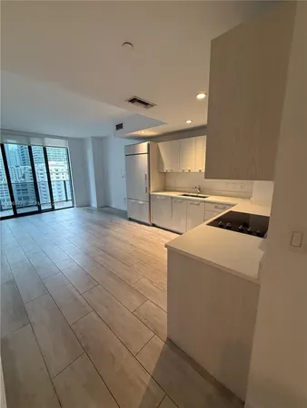 a view of kitchen and empty room with wooden floor