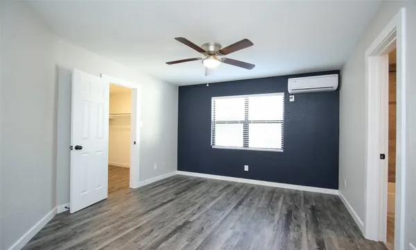 a view of an empty room with window and wooden floor