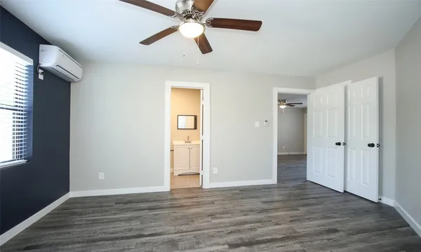 an empty room with wooden floor closet and windows