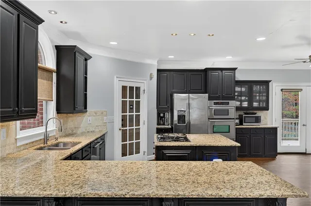 a kitchen with stainless steel appliances granite countertop a stove top oven a sink and a refrigerator