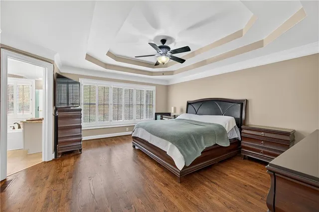 a bedroom with a bed and dresser with wooden floor