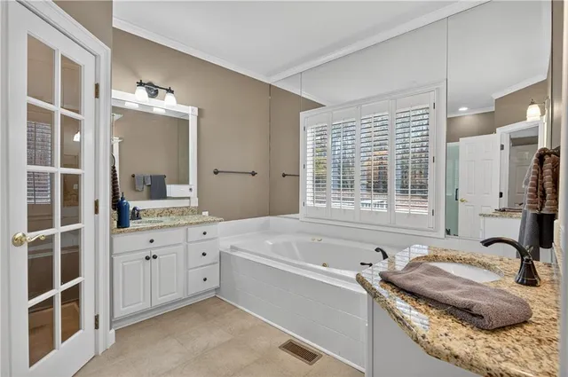 a bathroom with a granite countertop tub sink and mirror