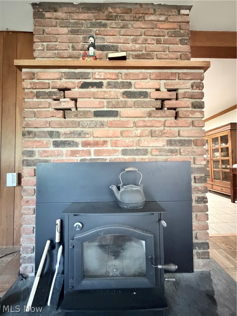 12590 Rockhaven Road Chesterland, OH 44026 - Photo 14 of 25 Brick fireplace with wood-burning stove insert, featuring a wood mantelpiece and an exposed brick chimney breast