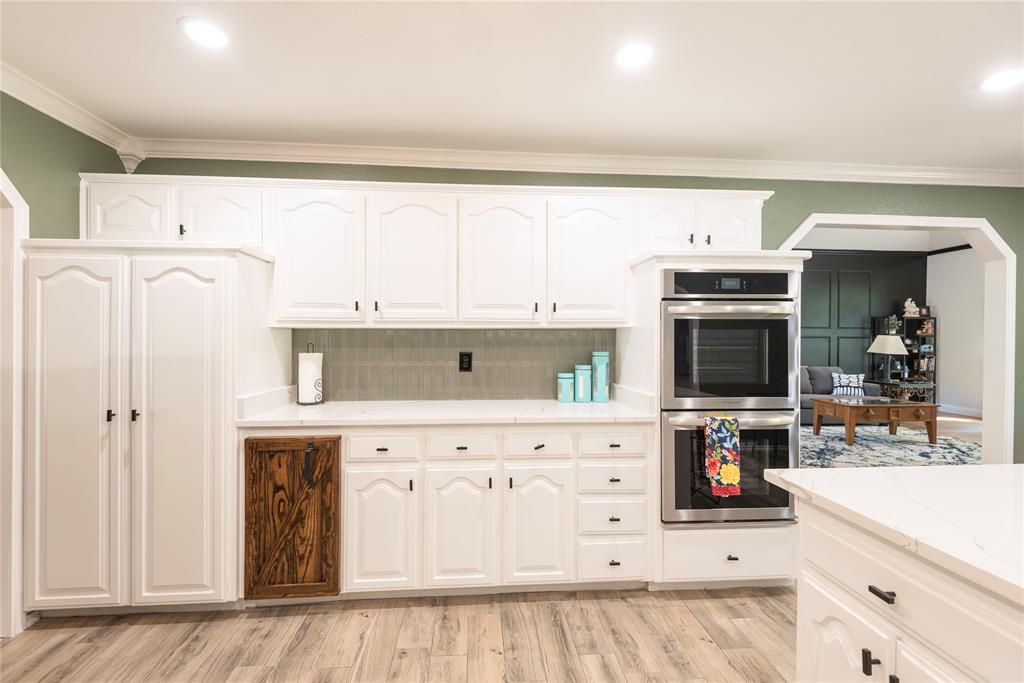 2020 Arbor Bend Road Bonham, TX 75418 - Photo 14 of 40 Kitchen with double oven, white cabinets, ornamental molding, light wood finished floors, and tasteful backsplash