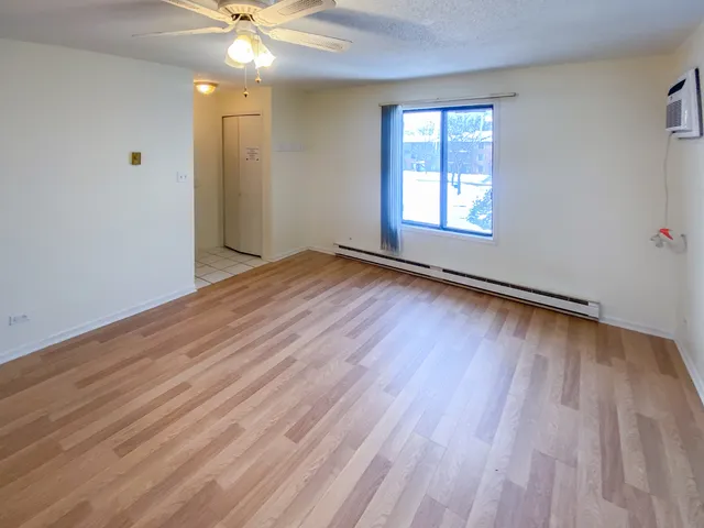 an empty room with wooden floor chandelier fan and windows