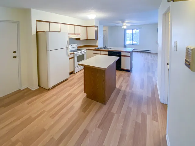 a kitchen with kitchen island wooden floors white appliances and cabinets
