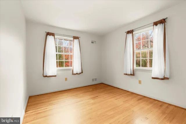 a view of a white house with a yard and large trees