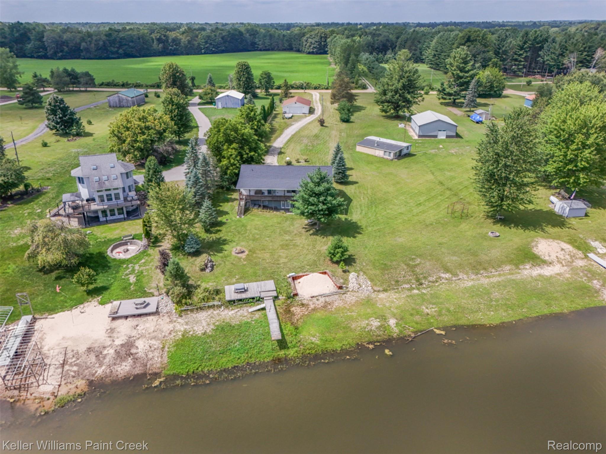 533 White Road Gladwin, MI 48624 - Photo 57 of 69 Expansive property featuring multiple structures, mature trees, and direct waterfront access with docks and a sandy area