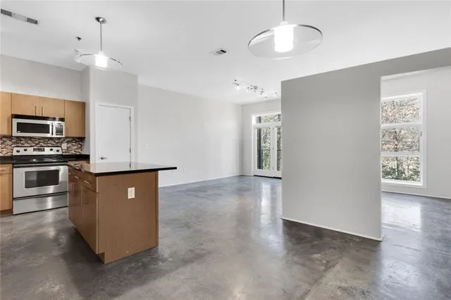 a kitchen with stainless steel appliances granite countertop a refrigerator a sink dishwasher a stove and a refrigerator with wooden floor